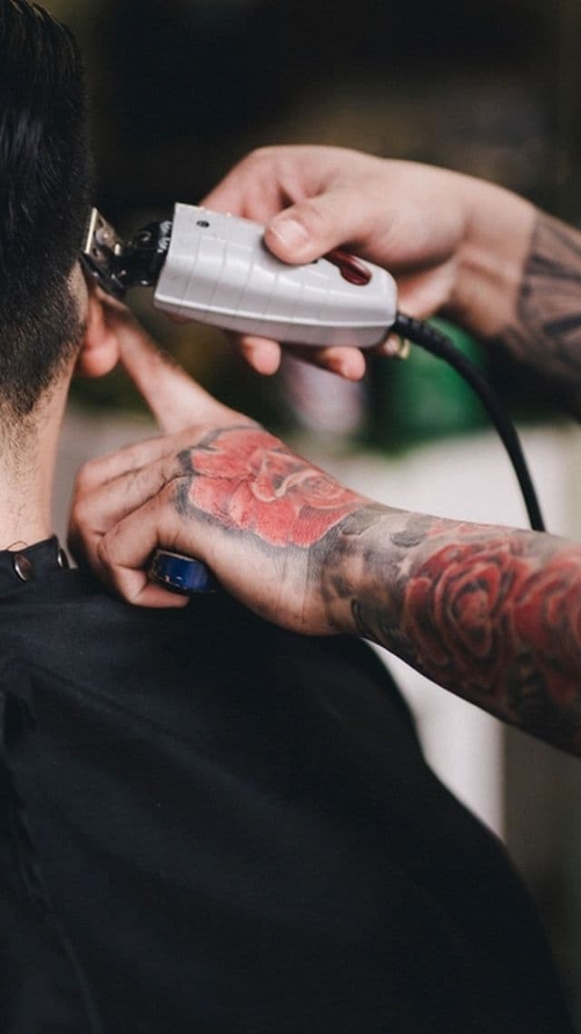 Máquina perfilando la nuca; el barbero lleva el brazo tatuado